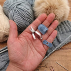 Lumos Lumos Mini Scissors in a hand, next to yarn and knitting